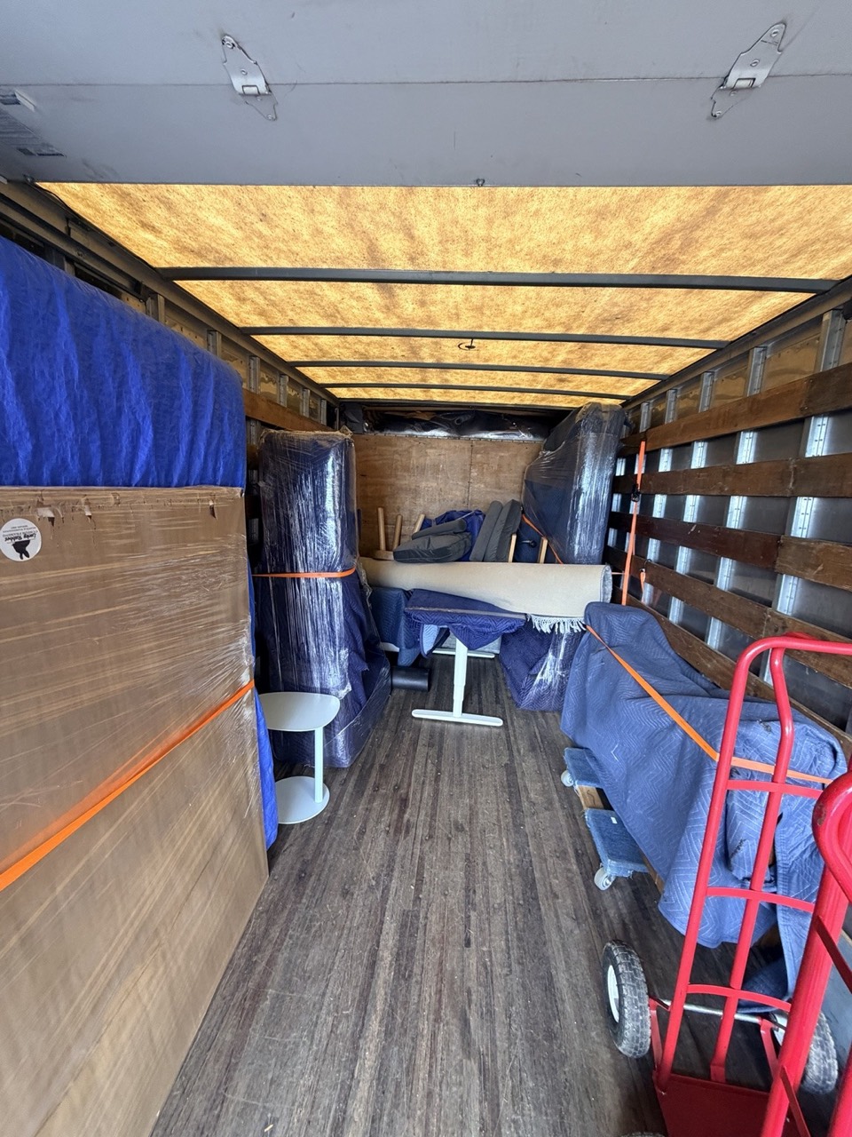 Furniture protected with moving blankets and straps inside an AT Moving truck.